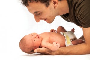 Young Caucasian father leaning over newborn son
