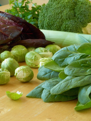 Leafy vegetables - spinach, Brussels sprouts, leeks, parsley, broccoli, lettuce - lying on a wooden table